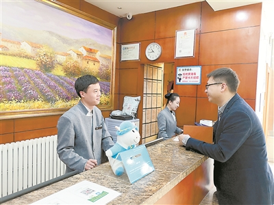 北京市西城區(qū)某快捷酒店的前臺接待曹健濤（左一）表示，他所在的快捷酒店成為越來越多來京出差干部的入住選擇，明顯感覺許多干部的節(jié)約意識增強了，會盤算著幫公家省錢了。