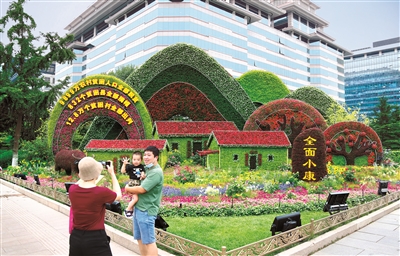 2021年6月，慶祝中國(guó)共產(chǎn)黨成立100周年主題花壇亮相長(zhǎng)安街沿線，西單東南角的全面小康主題花壇吸引市民駐足留影。 （圖片來源：人民視覺）