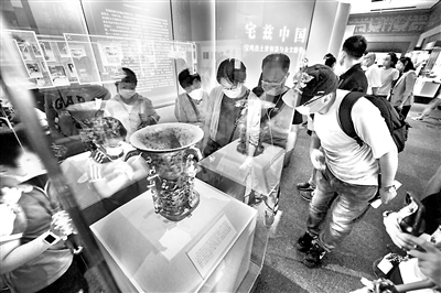距今3000多年的青銅何尊，器內(nèi)底部有122字銘文。其中的“宅茲中國”，是關于“中國”一詞最早的文字記載，彰顯了中華文化源遠流長的獨特魅力。圖為2020年8月18日，觀眾在國家博物館“宅茲中國——寶雞出土青銅器與金文精華”展上觀看展出的何尊。 （圖片來源：視覺中國）