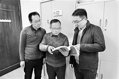圖為韓錫才（中）正在與同事們研究相關(guān)案情。尹琦琦 攝