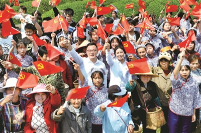 江西省德興市香屯街道辦江村千畝茶園，兩名基層扶貧干部揮舞著黨旗，和大家一起唱起了《唱支山歌給黨聽》。  （圖片來源：視覺中國）